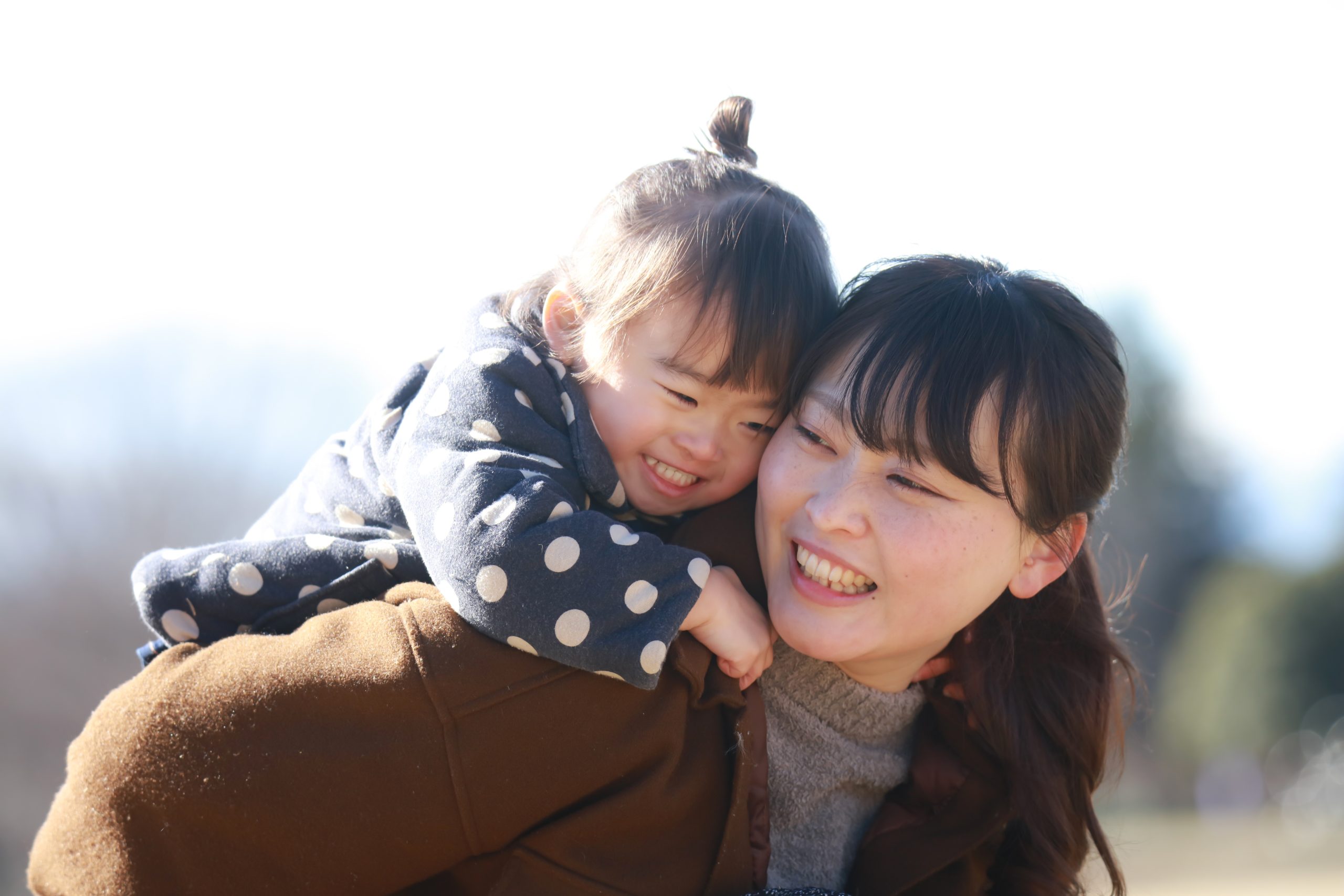 Mother piggy-backing her toddler, and both smiling