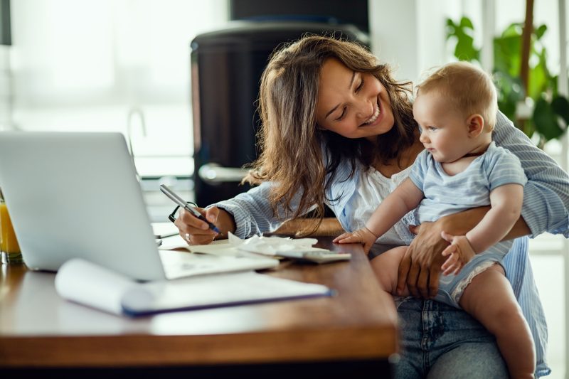 A mother making her will online sits in front of her home computer with her toddler on her lap.