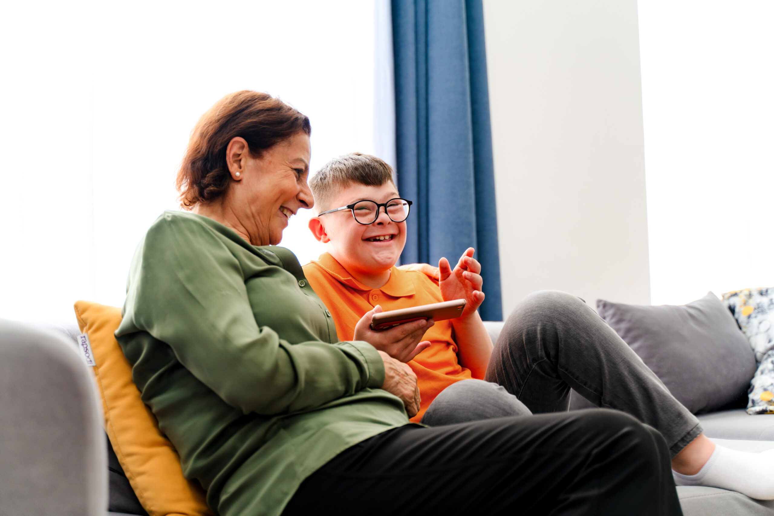 Little boy with down syndrome enjoy spending time with mother and watching mobile phone.